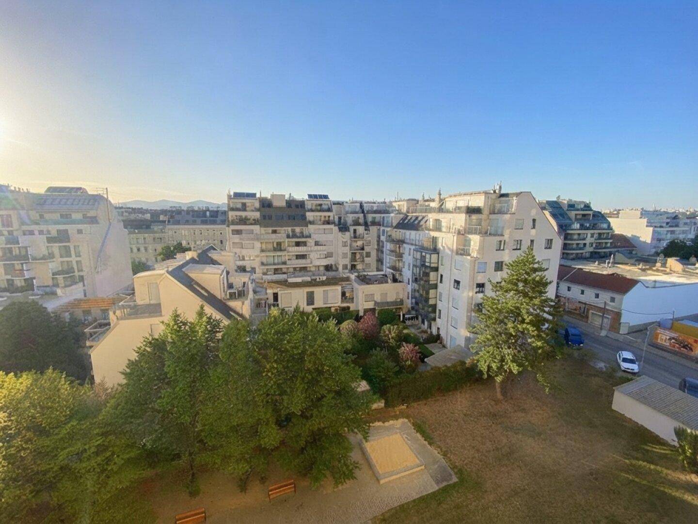 Weitläufiger Blick über eine städtische Wohngegend mit Parkanlagen und modernen Gebäuden.