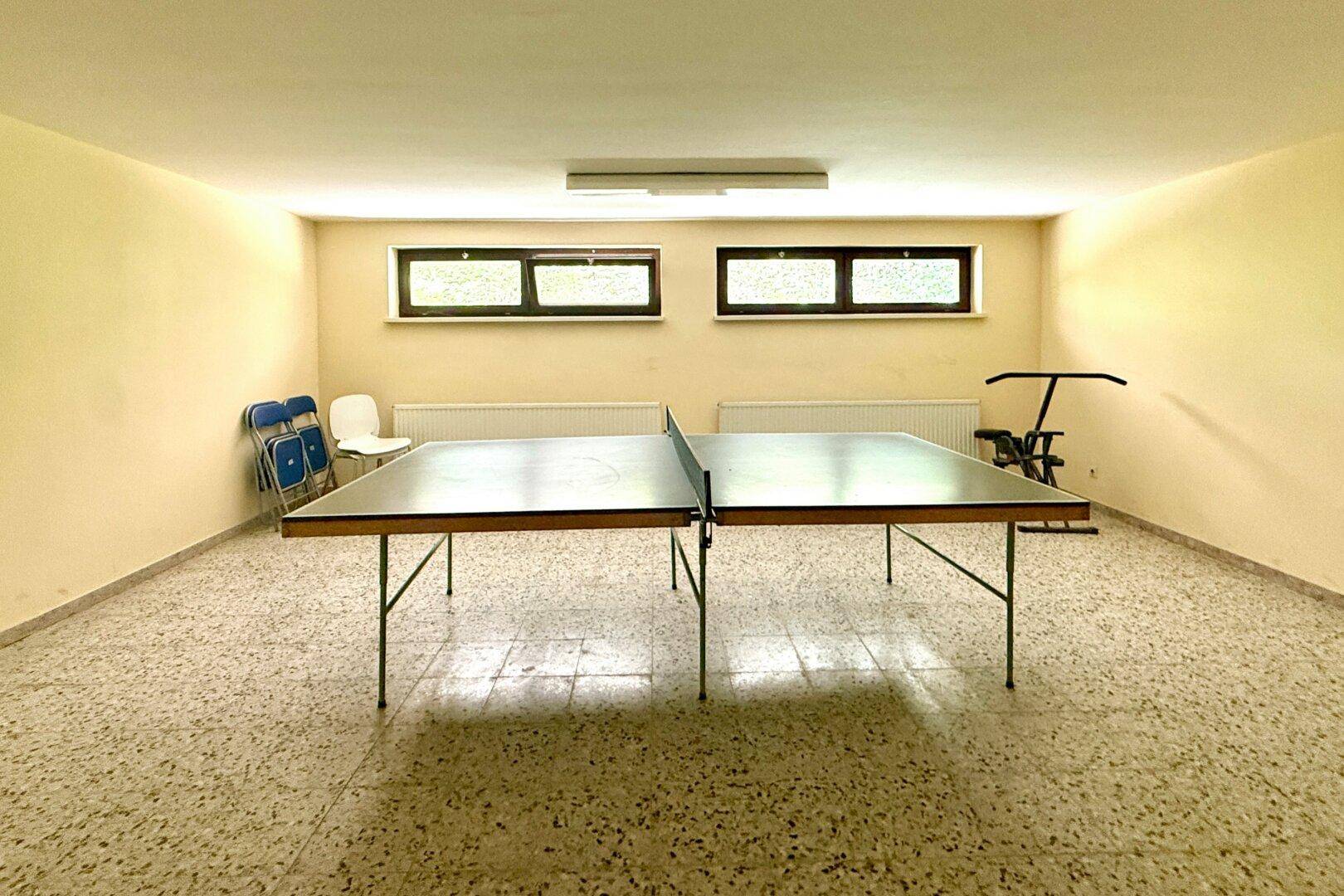 Geräumiger Kellerraum mit Tischtennisplatte, ideal für Freizeitaktivitäten und Sport.