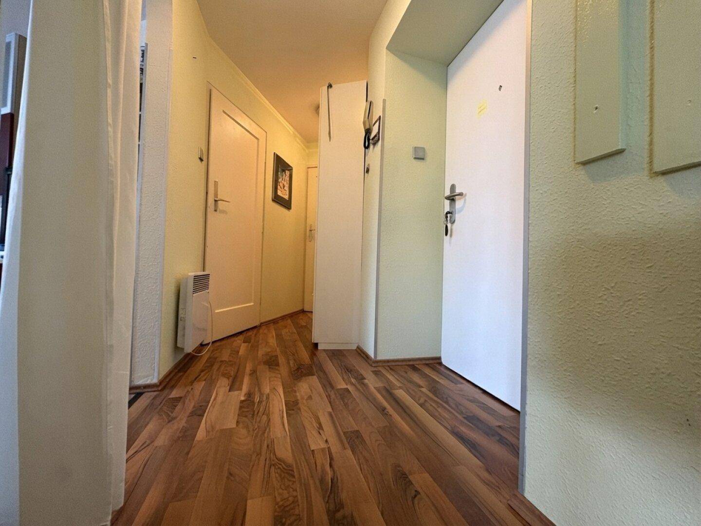 Heller Flur mit Laminatboden und Zugang zu verschiedenen Räumen, gut gepflegt.