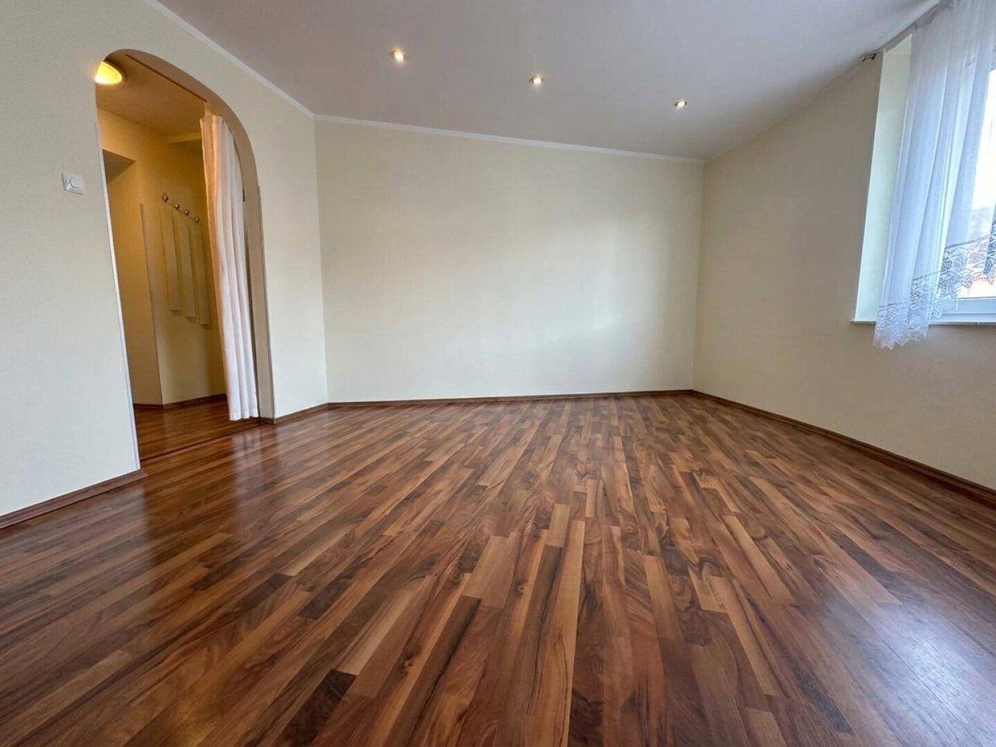Geräumiges Zimmer mit Laminatboden und einem Bogen zum Flur, ideal für flexible Nutzung.
