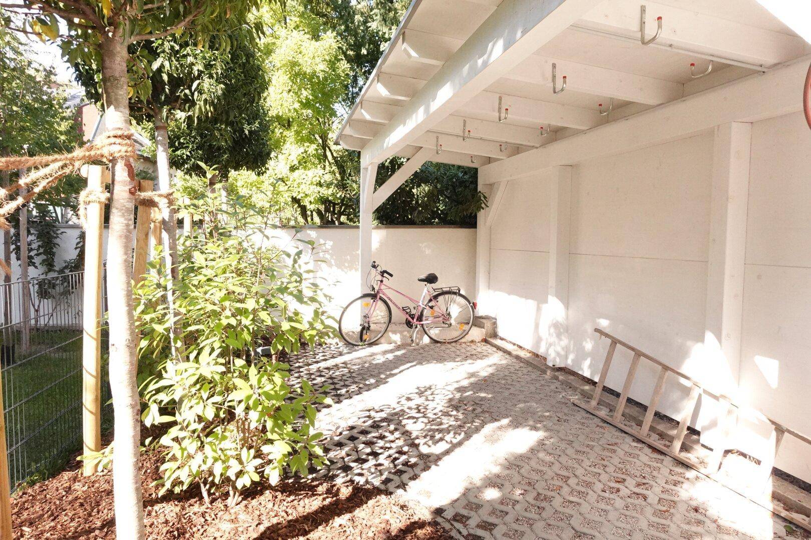 Überdachter Bereich, ideal als Carport oder Fahrradabstellplatz, mit Leiter und Fahrrad.