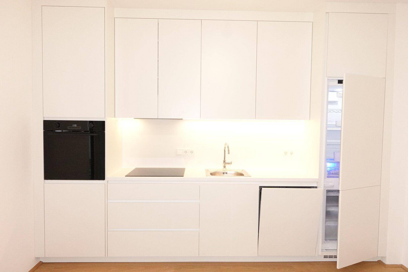 Moderne Einbauküche in Weiß mit integrierten Geräten und viel Stauraum.