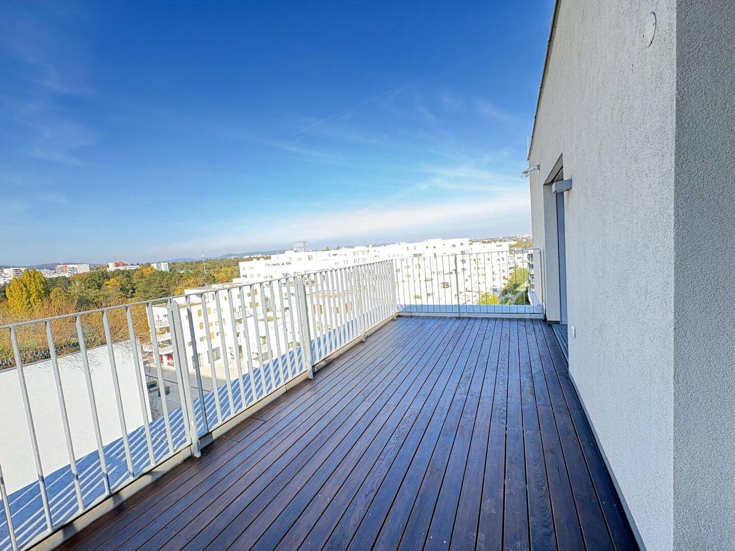 Großer Balkon mit Holzboden und weitem Blick über die Stadt und die Umgebung.
