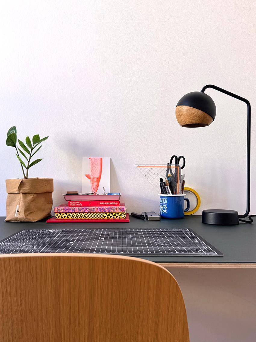 Detailansicht des Schreibtisches mit Büromaterialien und moderner Schreibtischlampe.
