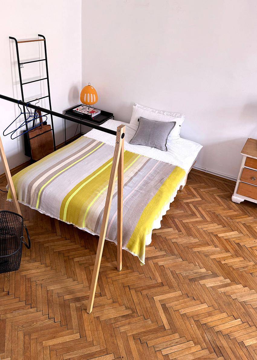 Schlafbereich mit Einzelbett, gestreifter Decke und elegantem Fischgrätparkettboden.