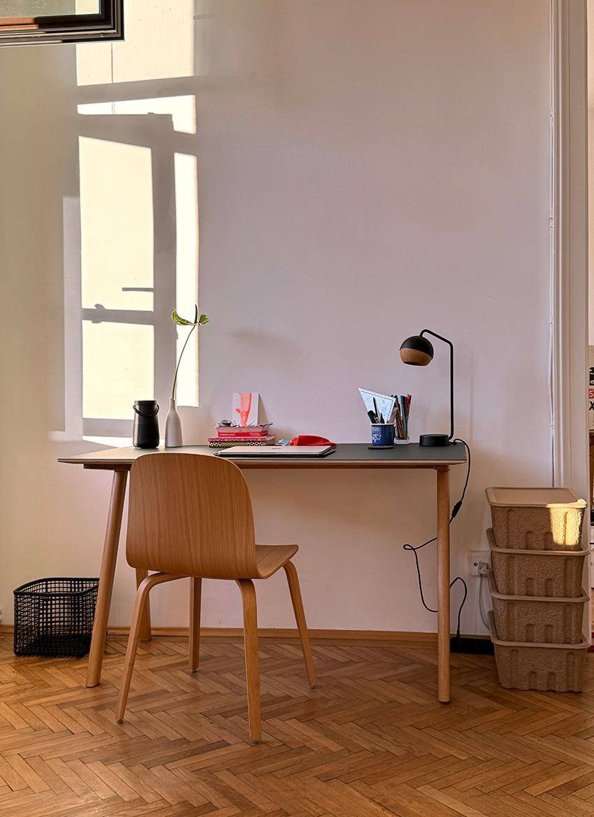Heller Arbeitsbereich mit Holzschreibtisch, Stuhl und natürlichem Lichteinfall durch das Fenster.