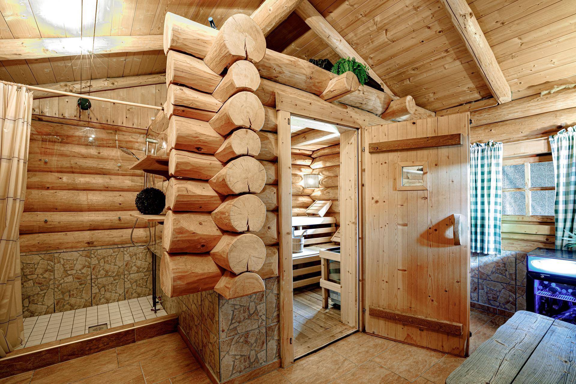 Rustikaler Wellnessbereich mit Holzsauna, Dusche und traditionellem Blockhaus-Design für entspannende Momente.