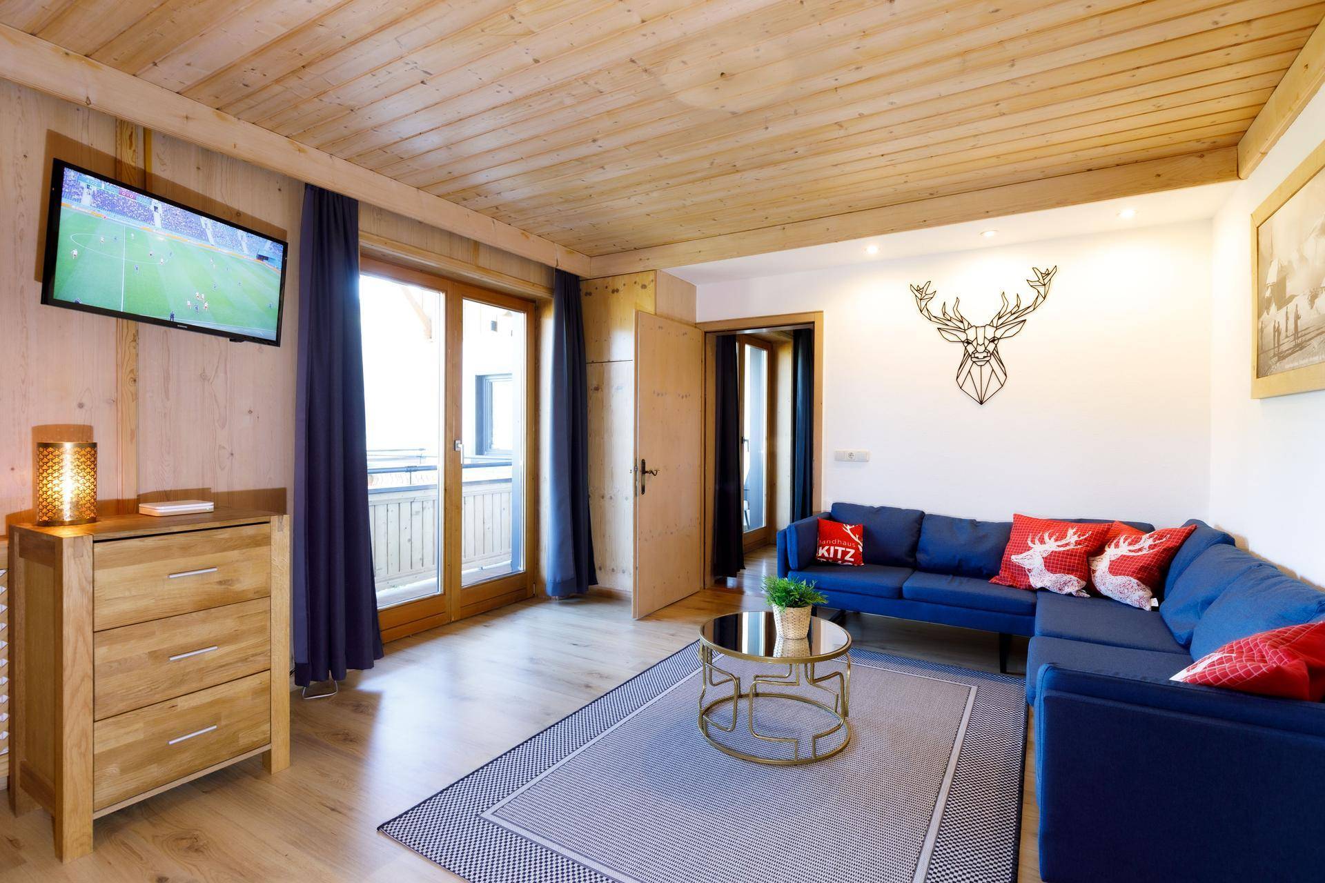 Modernes Wohnzimmer mit blauem Sofa, Holzboden und Zugang zu einem Balkon mit schöner Aussicht.