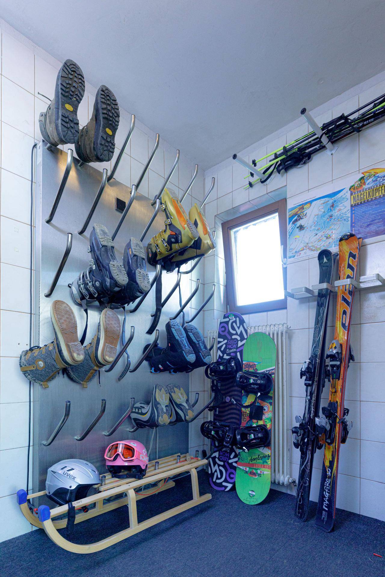 Praktischer Skiraum mit Wandhalterungen für Skischuhe, Skiern und Snowboards, ideal für Wintersportler.
