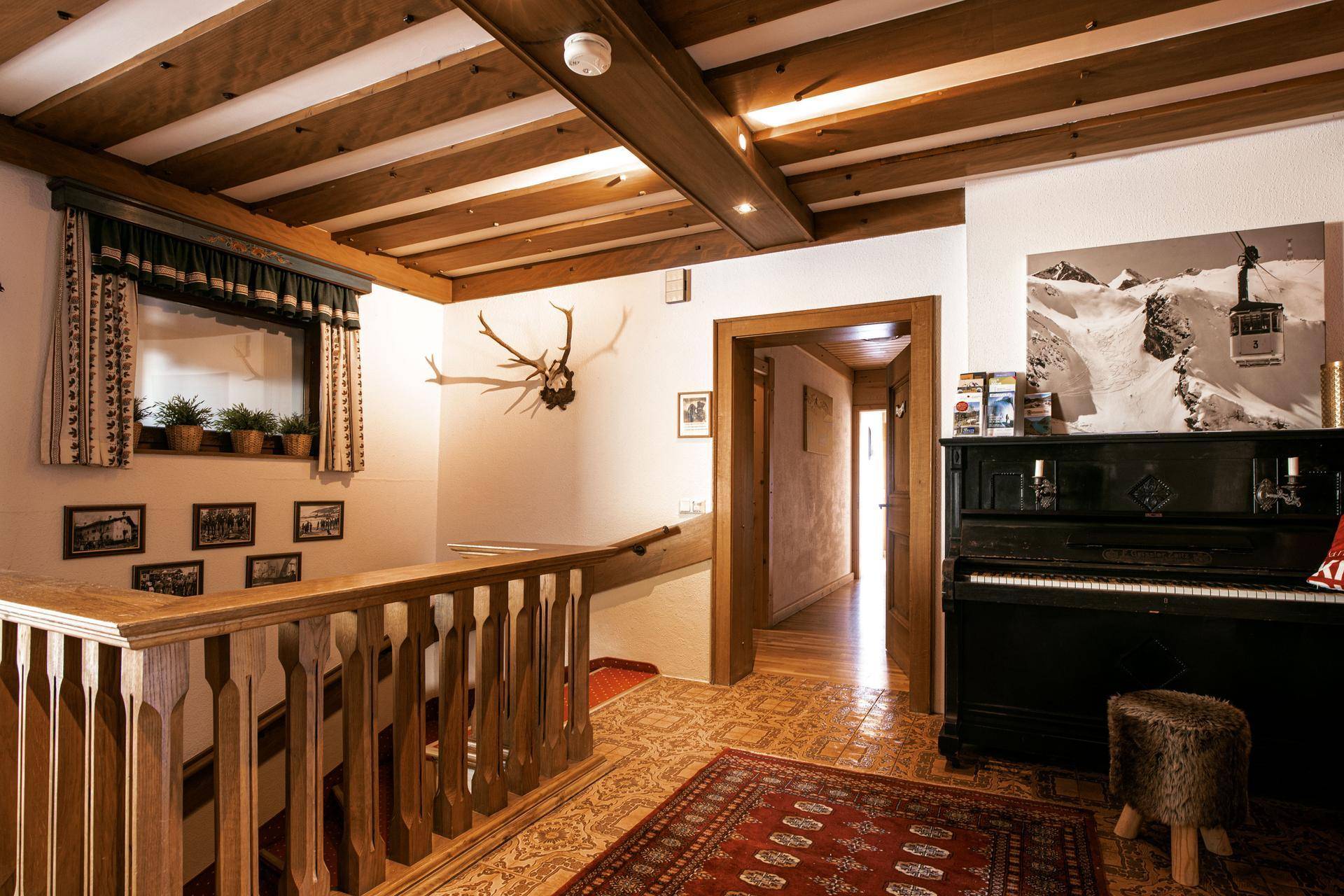 Heller Flur mit Holzgeländer, Teppichboden und einem Klavier, das zum Musizieren einlädt, in traditionellem Stil.