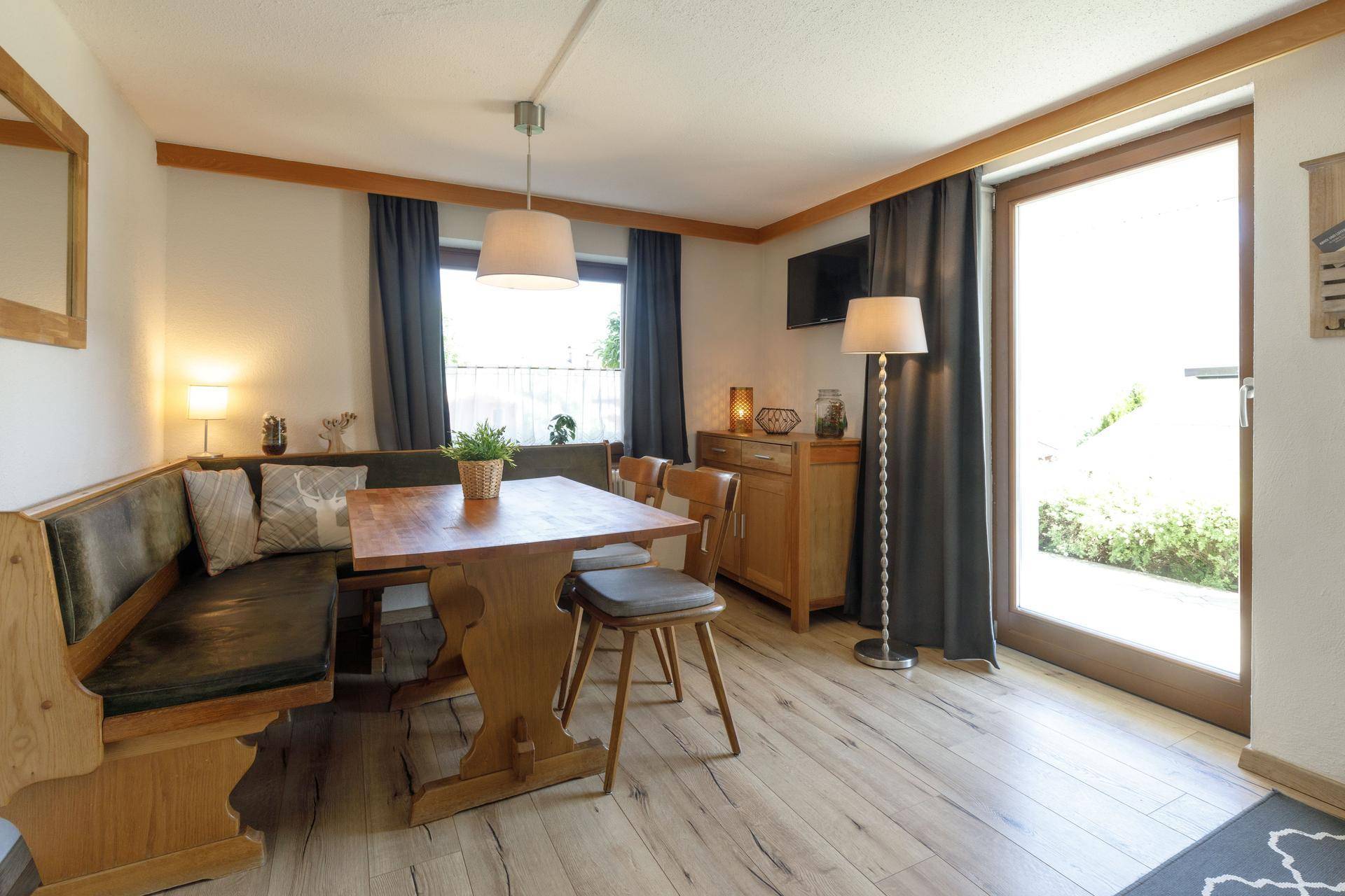 Gemütlicher Essbereich mit Eckbank, Holztisch und großem Fenster, das viel Licht hereinlässt.