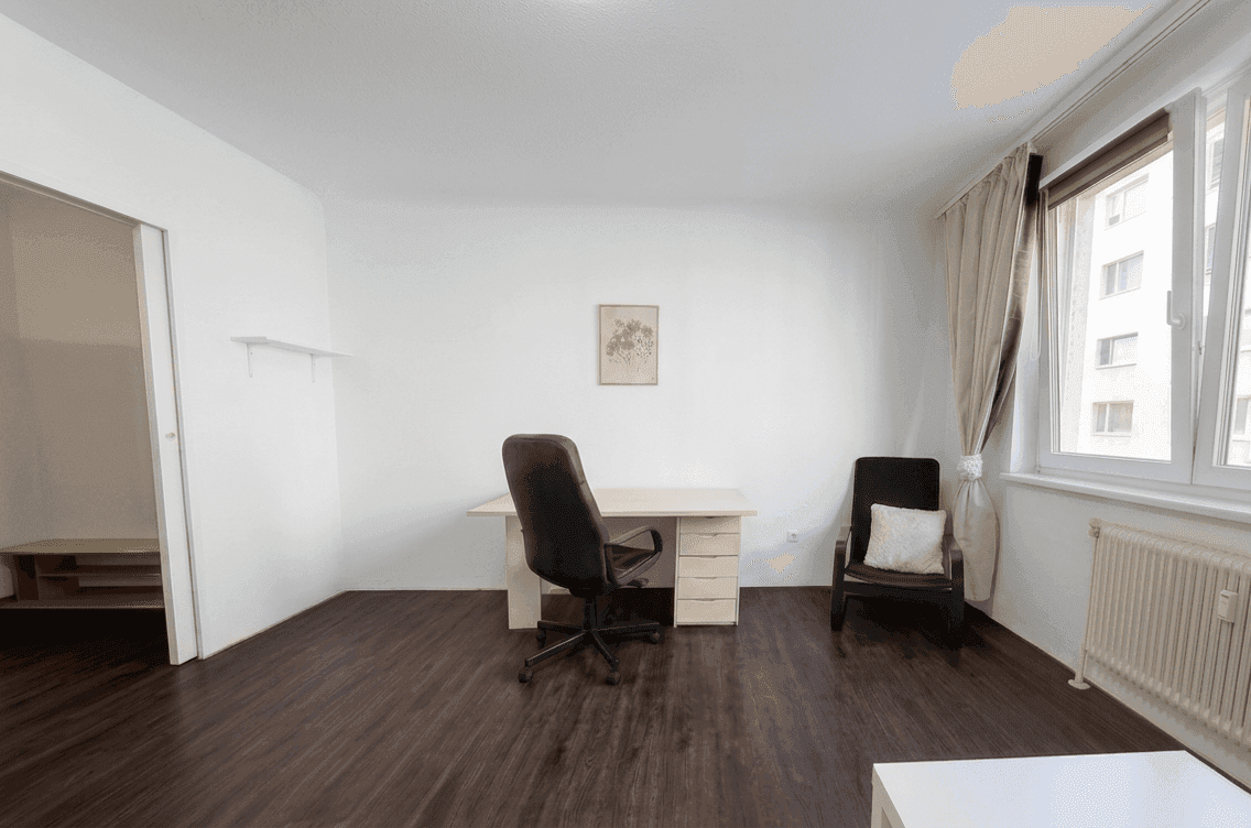 Helles Arbeitszimmer mit Schreibtisch, Bürostuhl und großem Fenster.
