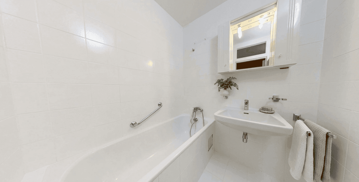 Helles Badezimmer mit Badewanne, Waschbecken und weißen Fliesen.