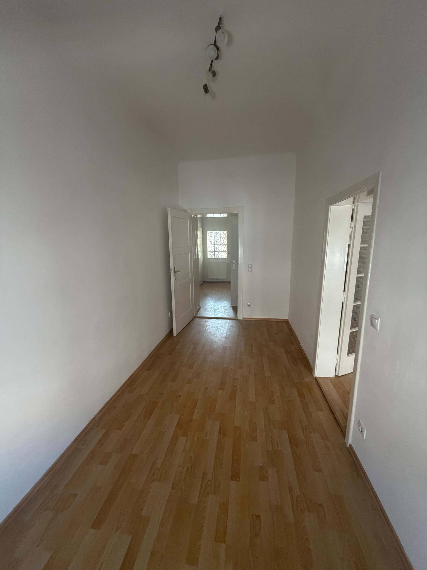 Heller Flur mit Laminatboden und Türen, die zu verschiedenen Räumen führen.