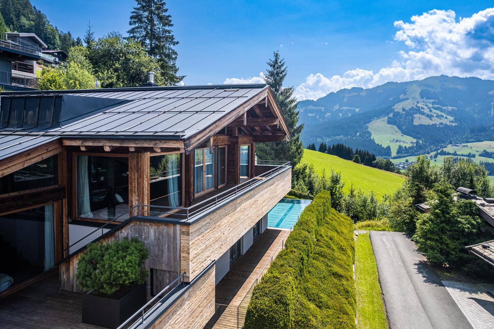 Moderne Villa mit Holzfassade, Balkonen und weitem Blick auf die alpine Landschaft.