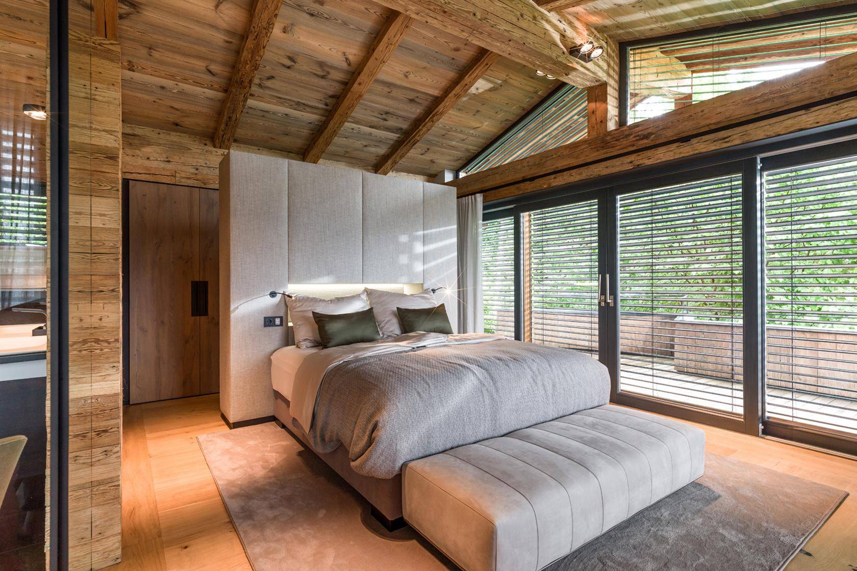 Helles Schlafzimmer mit großem Bett, Holzbalkendecke und Zugang zur Terrasse.