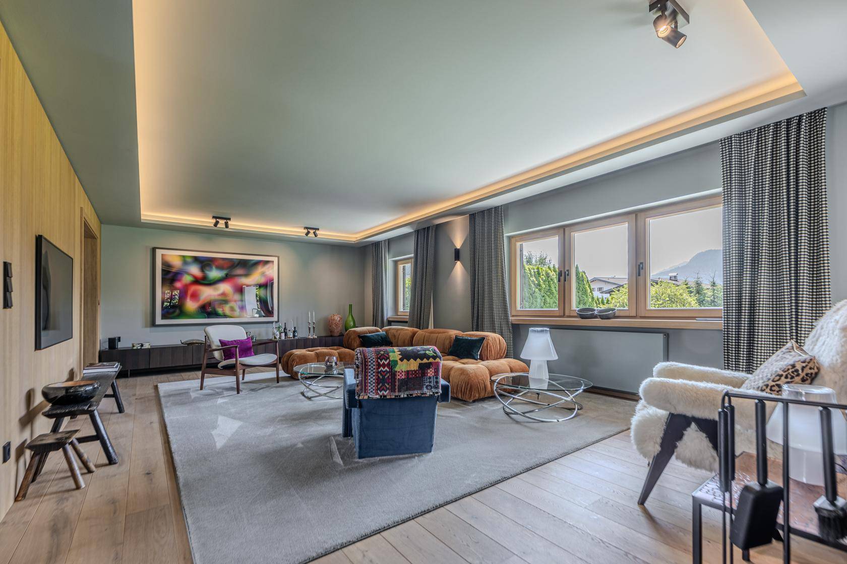 Helles Wohnzimmer mit modernen Möbeln, Holzboden und indirekter Beleuchtung.