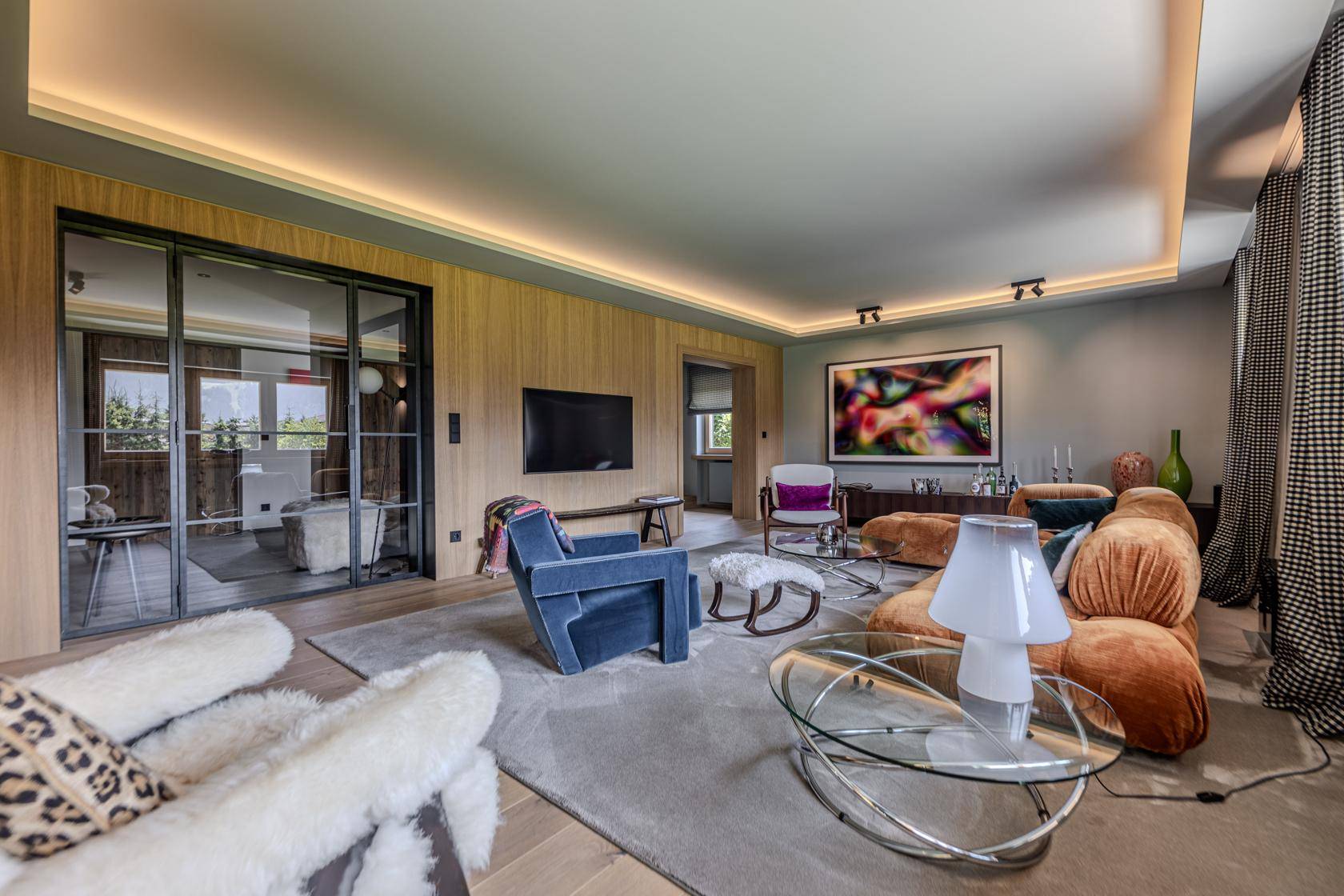 Modernes Wohnzimmer mit Holzwänden, indirekter Beleuchtung und stilvollen Möbeln.