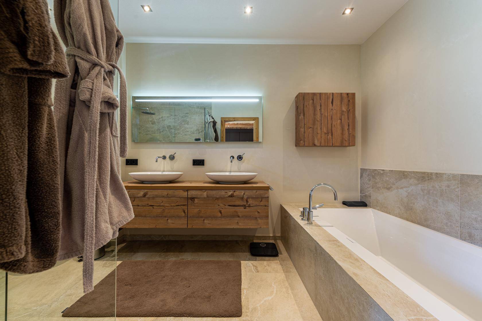 Modernes Badezimmer mit Doppelwaschbecken, Badewanne und Holzelementen.