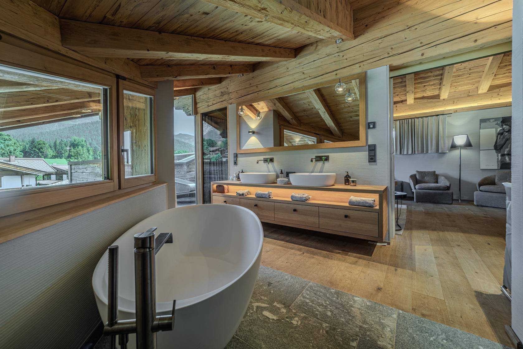 Modernes Badezimmer mit freistehender Badewanne, Doppelwaschbecken und Blick auf die umliegende Berglandschaft.
