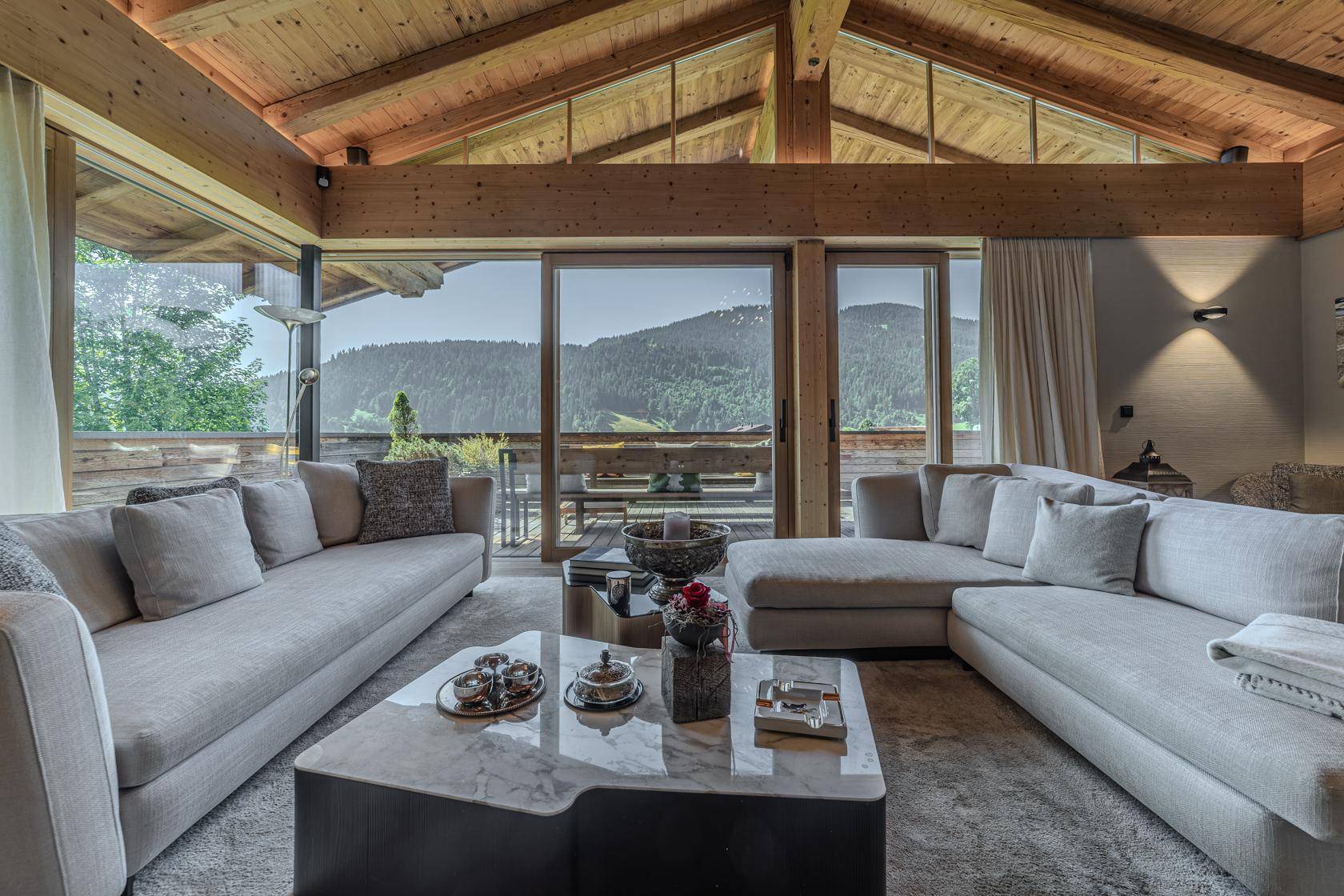 Helles Wohnzimmer mit großen Glasfronten, die einen weiten Blick auf die Berge und die Natur bieten.