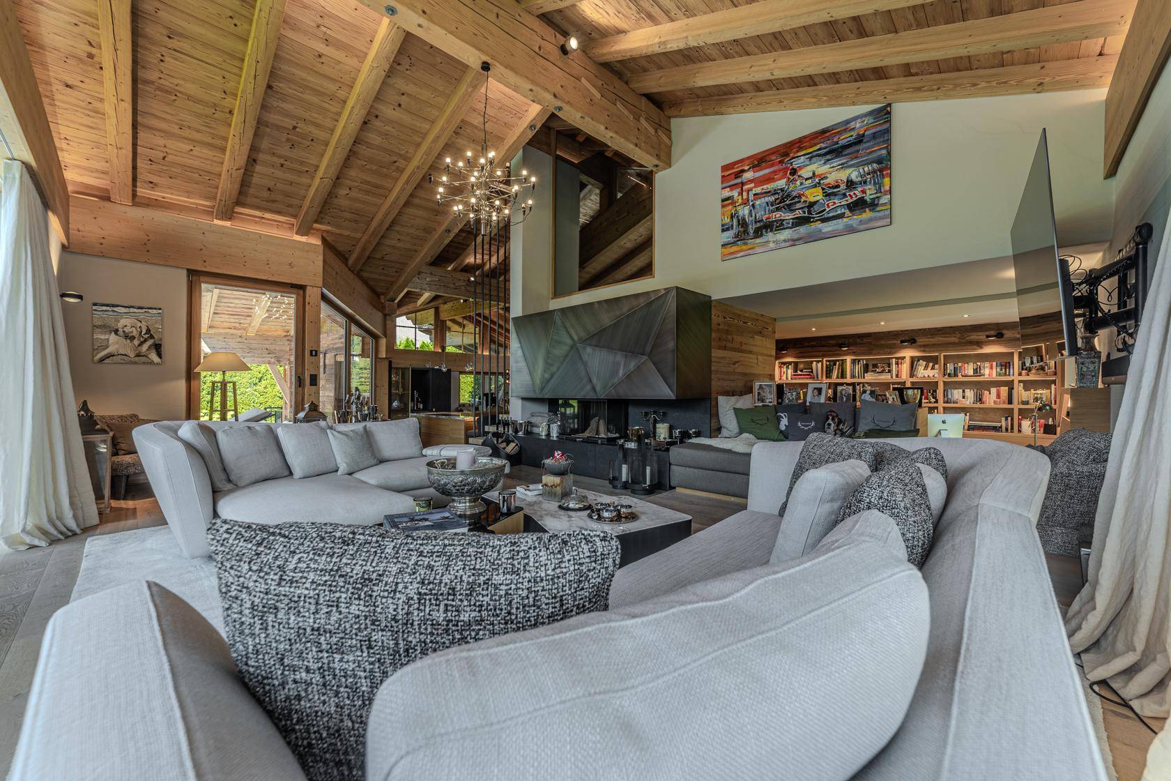 Geräumiges Wohnzimmer mit hohen Holzdecken, modernem Kamin und bequemen Sofas, ideal zum Entspannen.