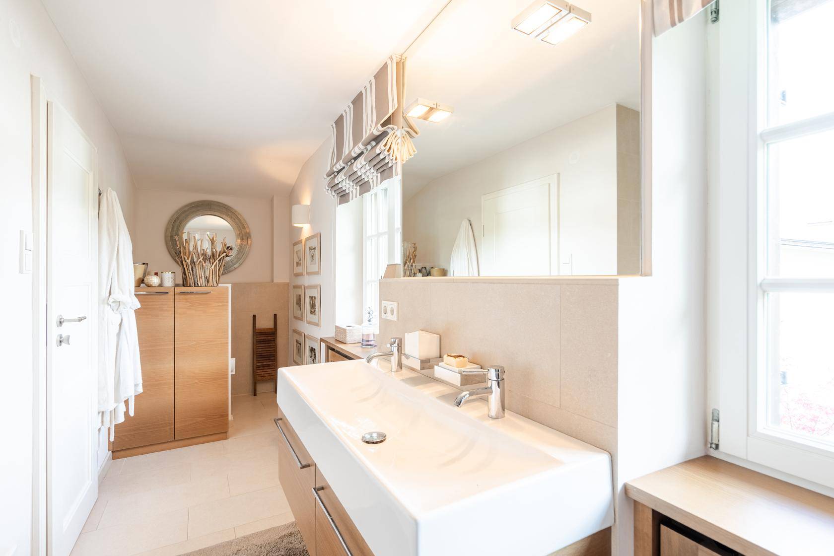 Modernes Badezimmer mit Doppelwaschbecken, großem Spiegel und Fenster für Tageslicht.