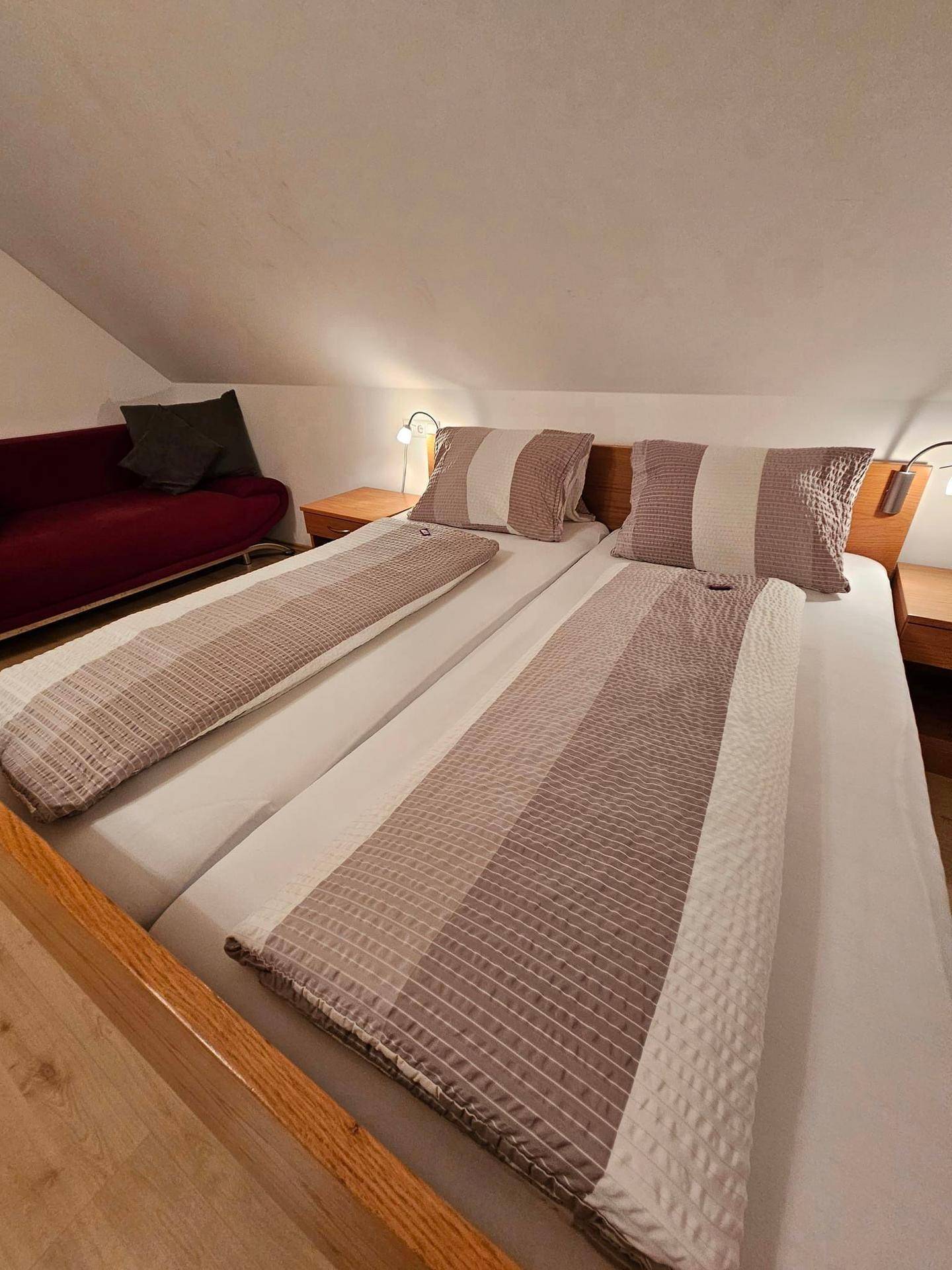 Nahaufnahme von zwei Einzelbetten mit gestreiften Bettdecken in einem gemütlichen Schlafzimmer.
