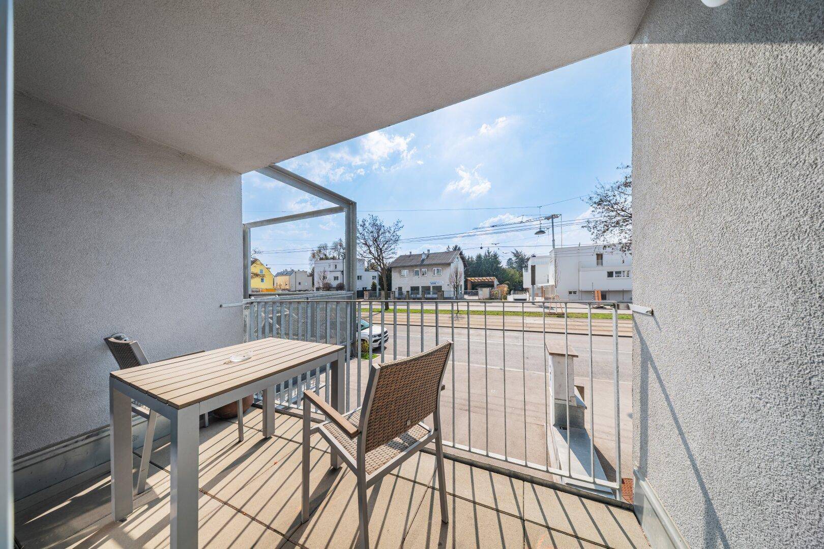 Kleiner Balkon mit Tisch und Stühlen, bietet einen Blick auf die Straße und die Umgebung.