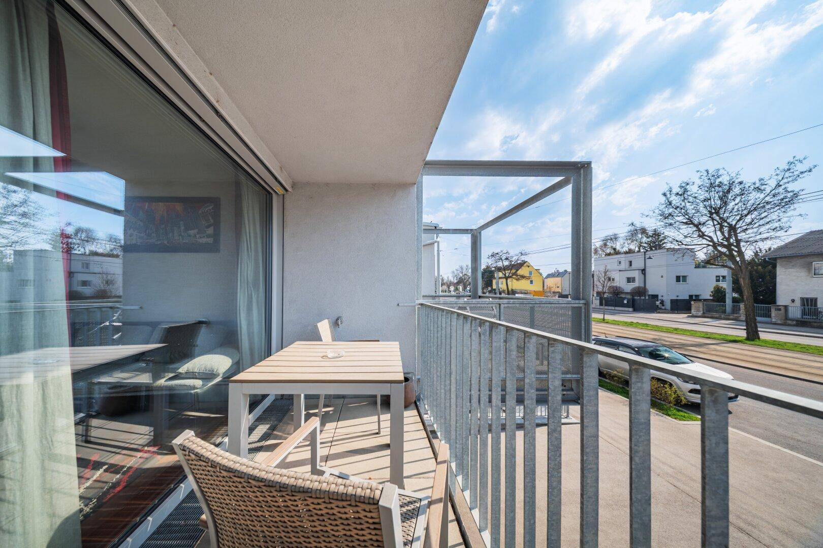 Sonniger Balkon mit Metallgeländer und Blick auf die Straße, verbunden mit dem Innenbereich.