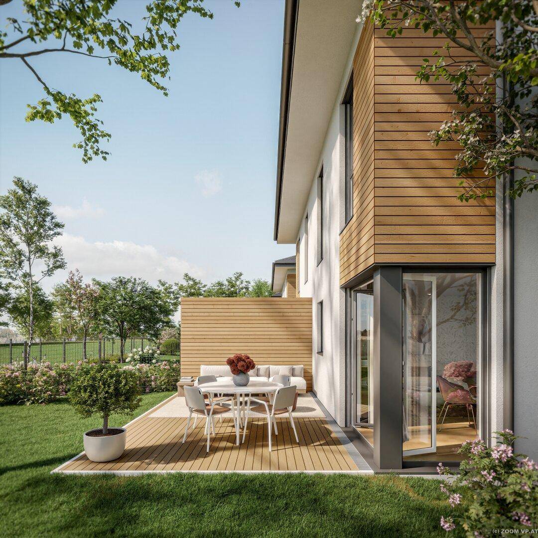 Nahaufnahme der Holzterrasse mit Esstisch und Zugang zum Innenbereich des Hauses.