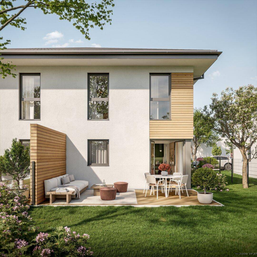 Seitliche Ansicht der Doppelhaushälfte mit Holzterrasse, Gartenmöbeln und grüner Umgebung.
