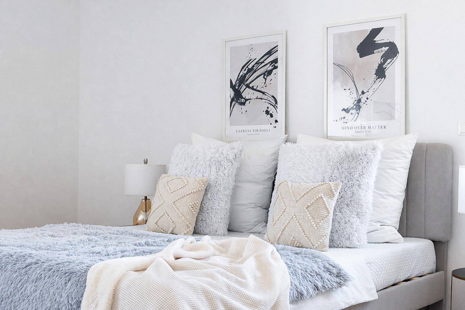 Gemütliches Schlafzimmer mit weichen Kissen und moderner Kunst an der Wand.