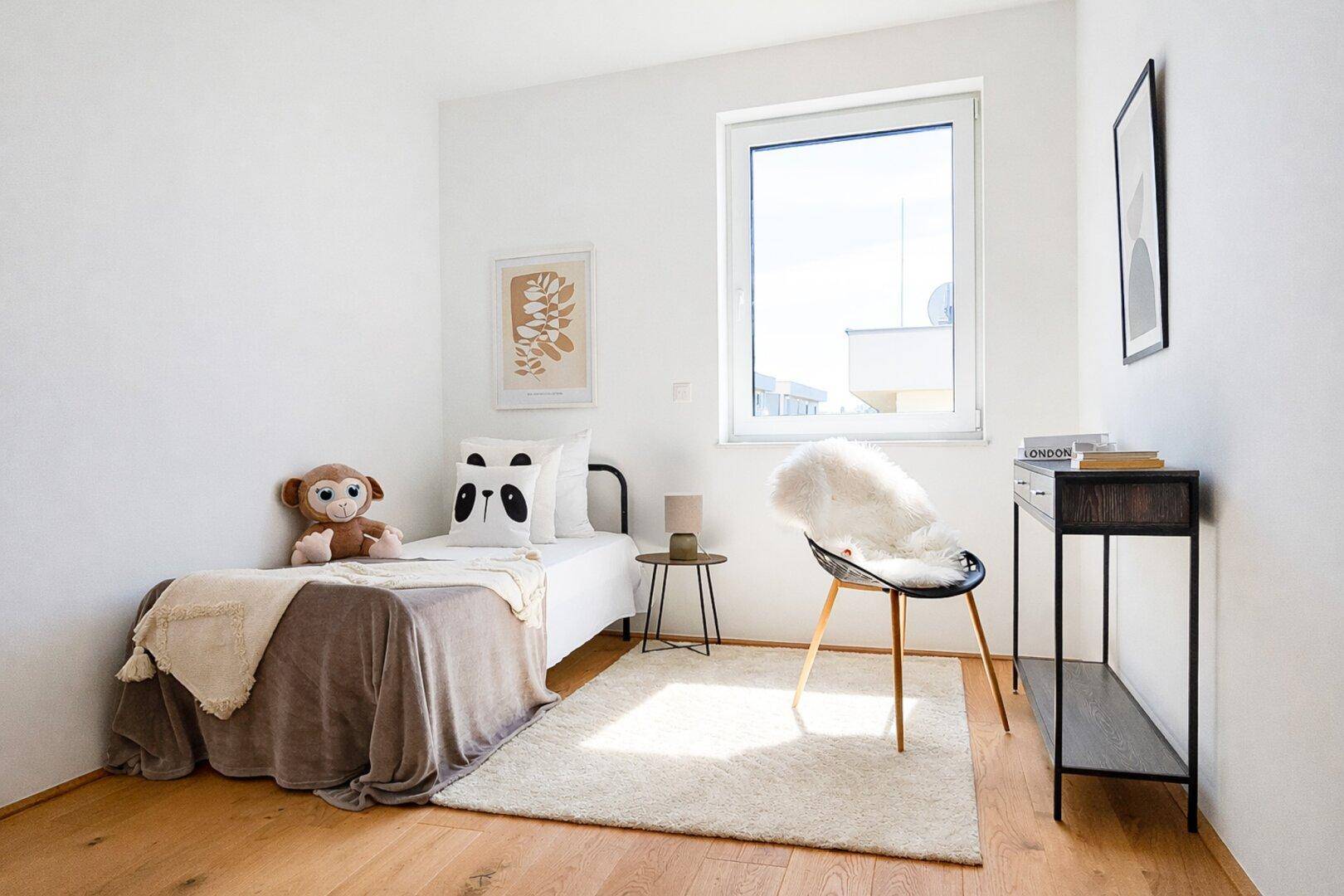 Kinderzimmer oder Gästezimmer mit Einzelbett, Schreibtisch und großem Fenster.