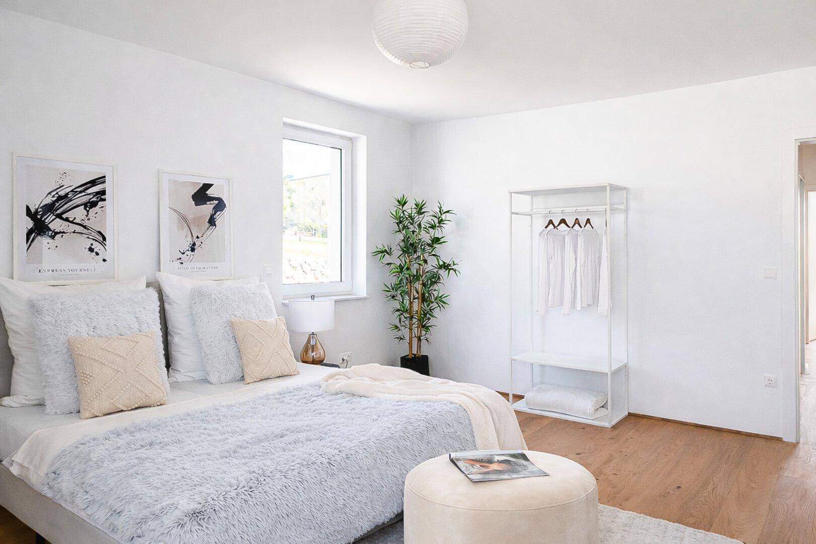 Geräumiges Schlafzimmer mit viel Tageslicht, Holzboden und minimalistischer Einrichtung.
