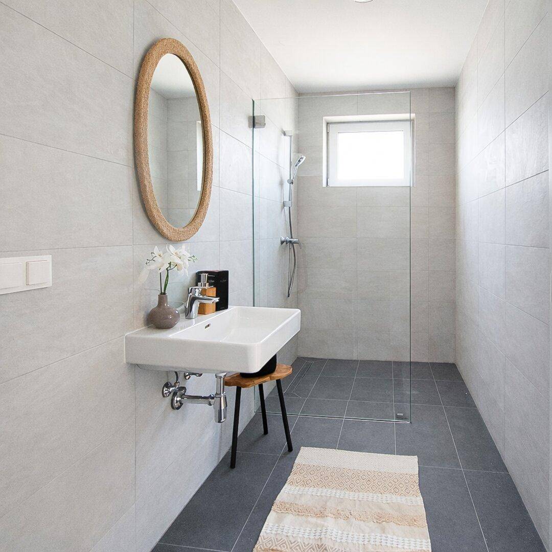 Modernes Badezimmer mit begehbarer Dusche, Einzelwaschbecken und hellen Fliesen.