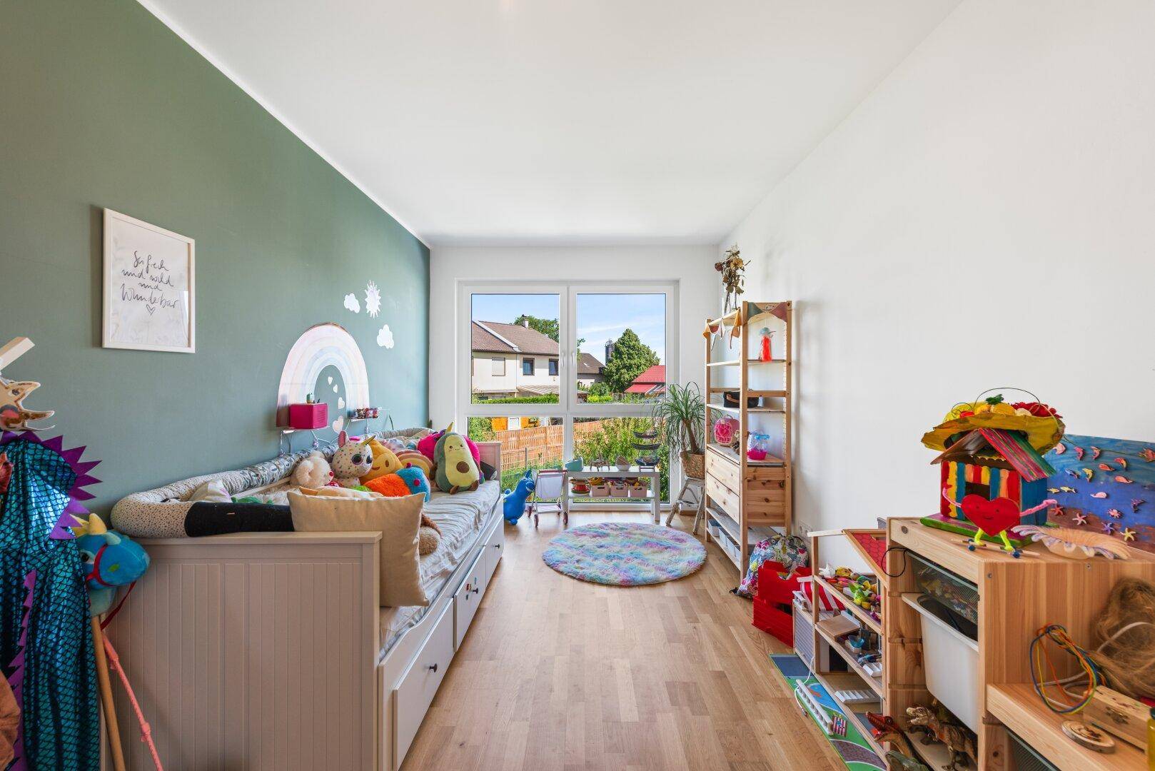 Farbenfrohes Kinderzimmer mit Bett, Spielsachen und grüner Akzentwand, ideal für Kinder.