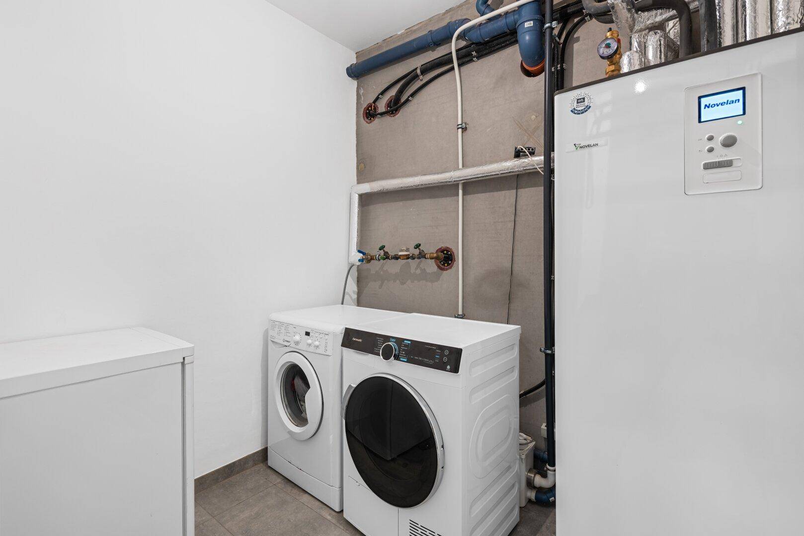Praktischer Hauswirtschaftsraum im Keller mit Waschmaschine, Trockner und Heizungsanlage.