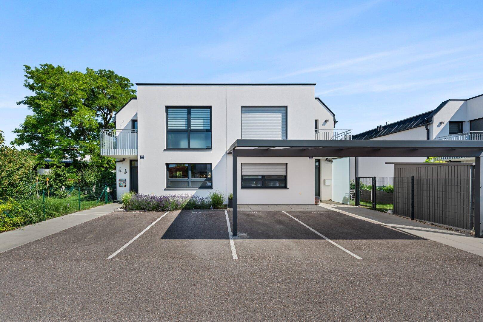 Moderne Doppelhaushälfte mit Carport und Stellplätzen vor dem Eingangsbereich.
