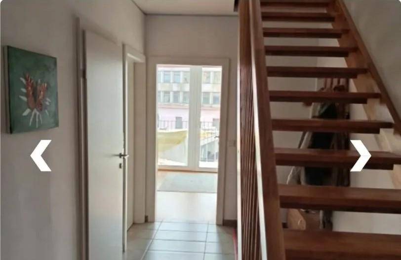 Heller Flur mit Holztreppe und Zugang zu einem Außenbereich, der viel Licht hereinlässt und einladend wirkt.