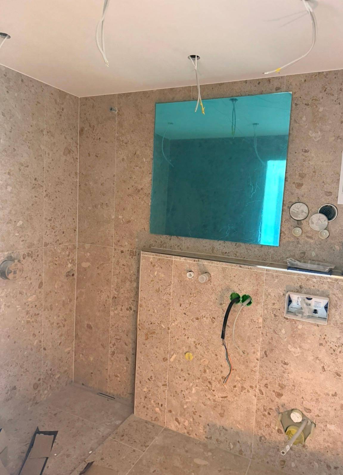Badezimmer im Bau mit beigefarbenen Fliesen und vorbereiteten Anschlüssen.