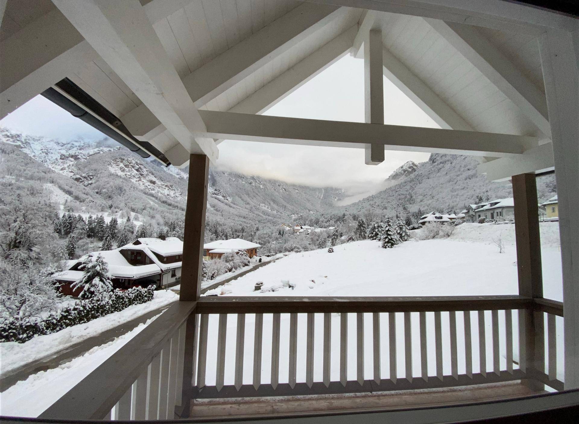 Balkon mit Holzbalken und atemberaubendem Blick auf die verschneite Berglandschaft.