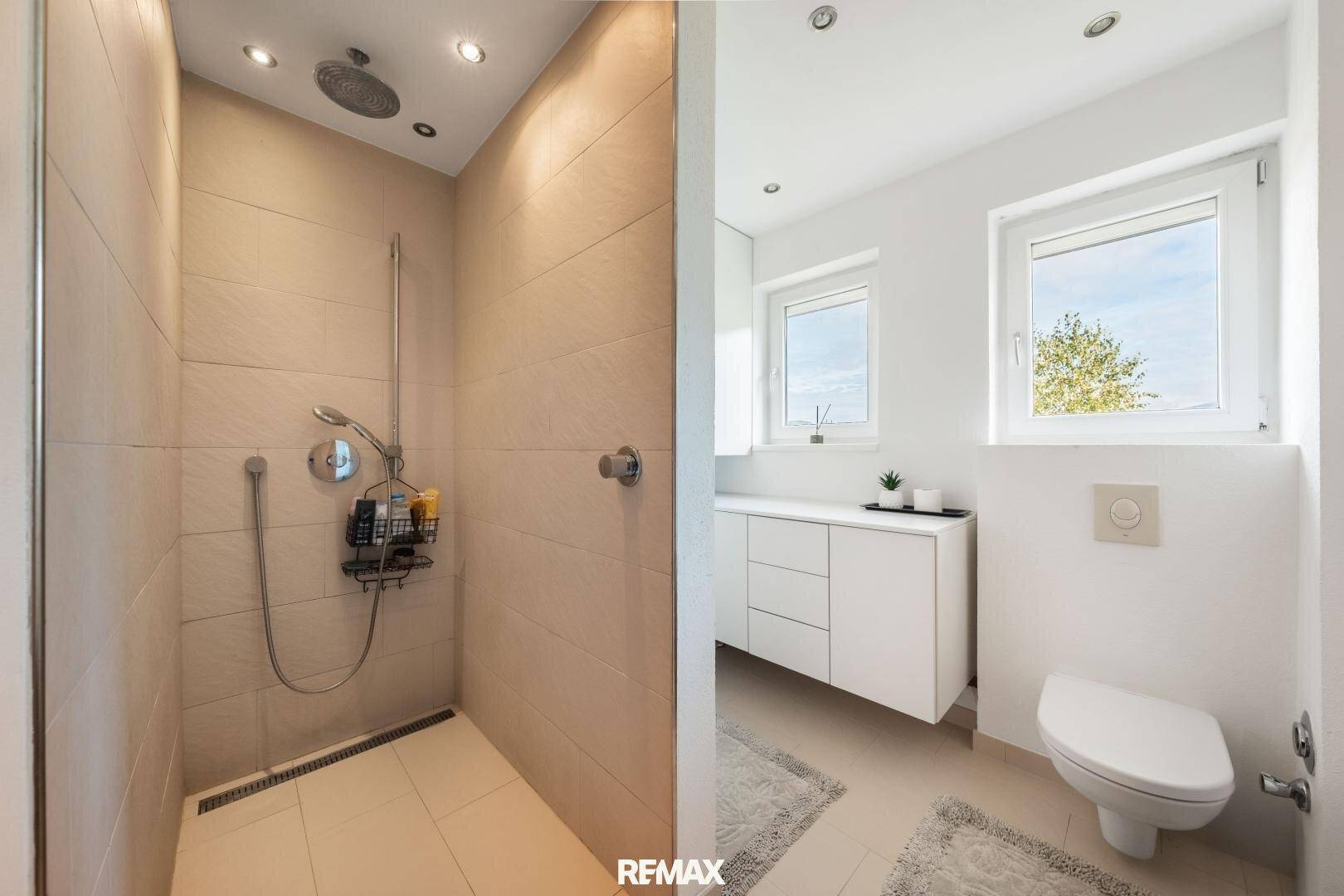 Modernes Badezimmer mit begehbarer Dusche, Wand-WC und hellen Fliesen.