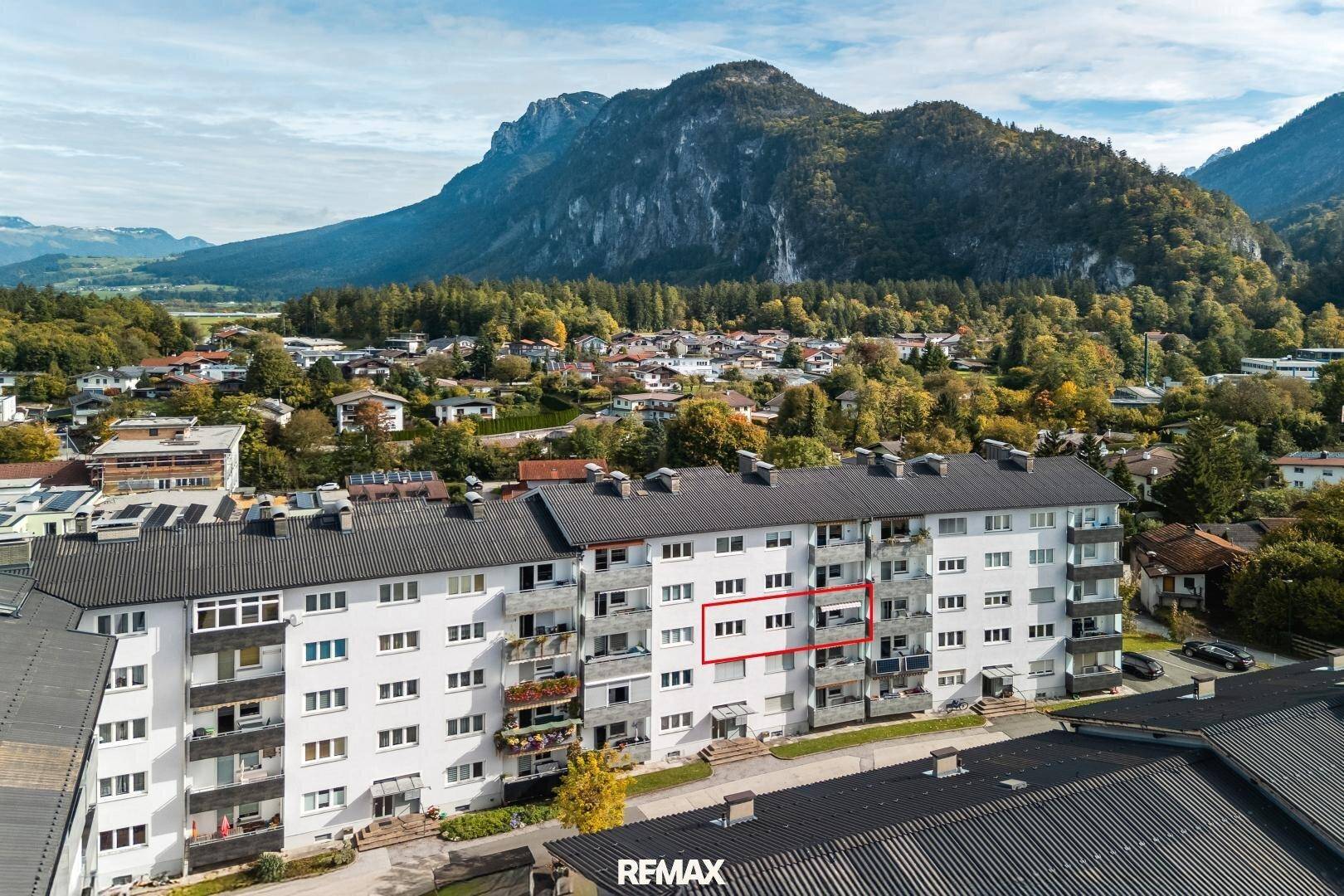 Luftaufnahme eines Wohngebäudes in bergiger Umgebung mit Balkonen und grüner Landschaft.