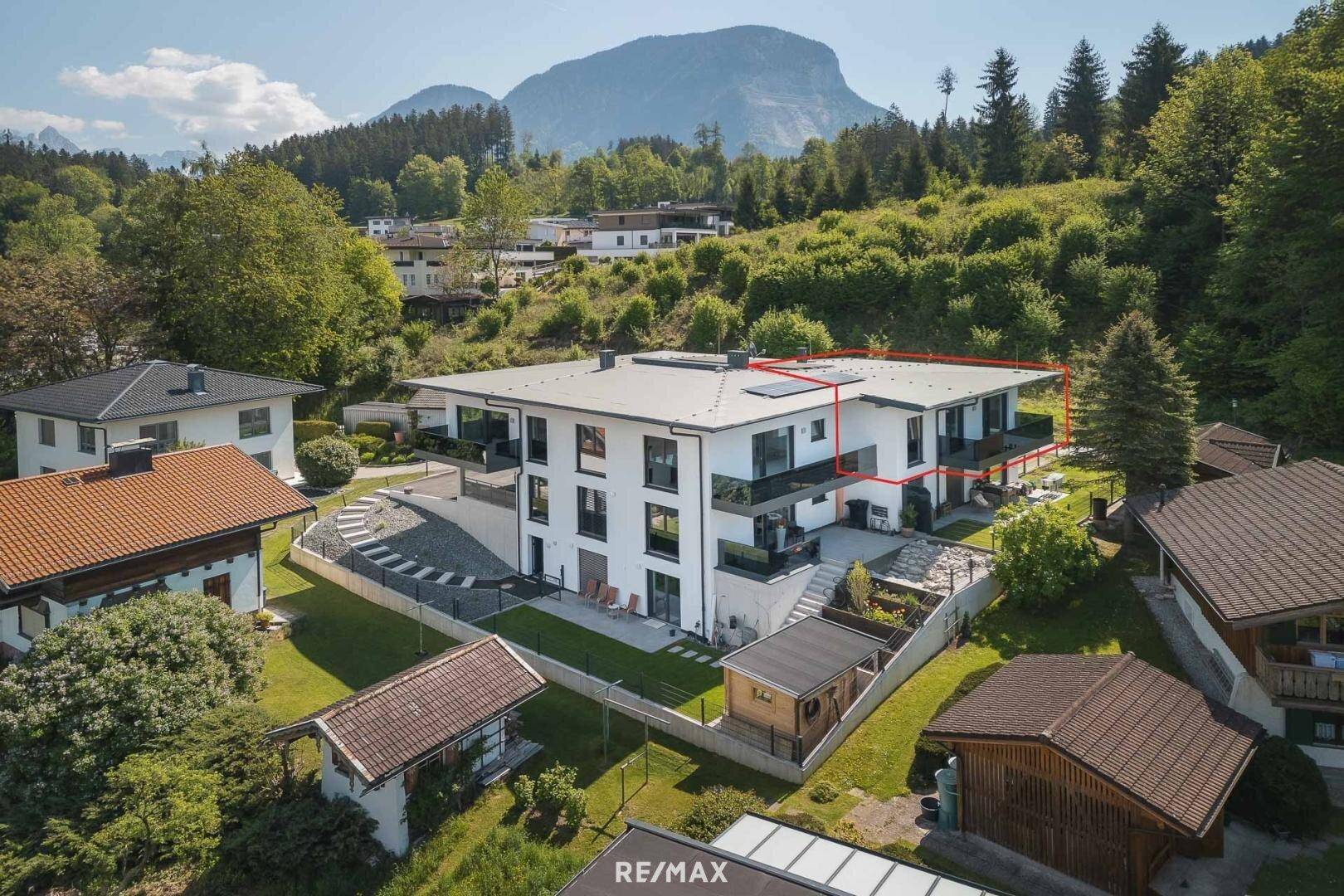 Moderne Wohnanlage in grüner Umgebung mit Bergblick und Flachdacharchitektur.