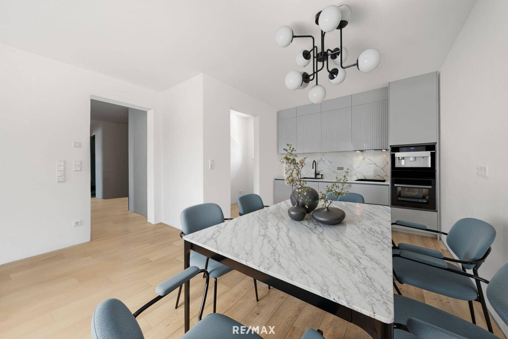 Moderner Essbereich mit Marmortisch und Blick auf die stilvolle, eingebaute Küche.