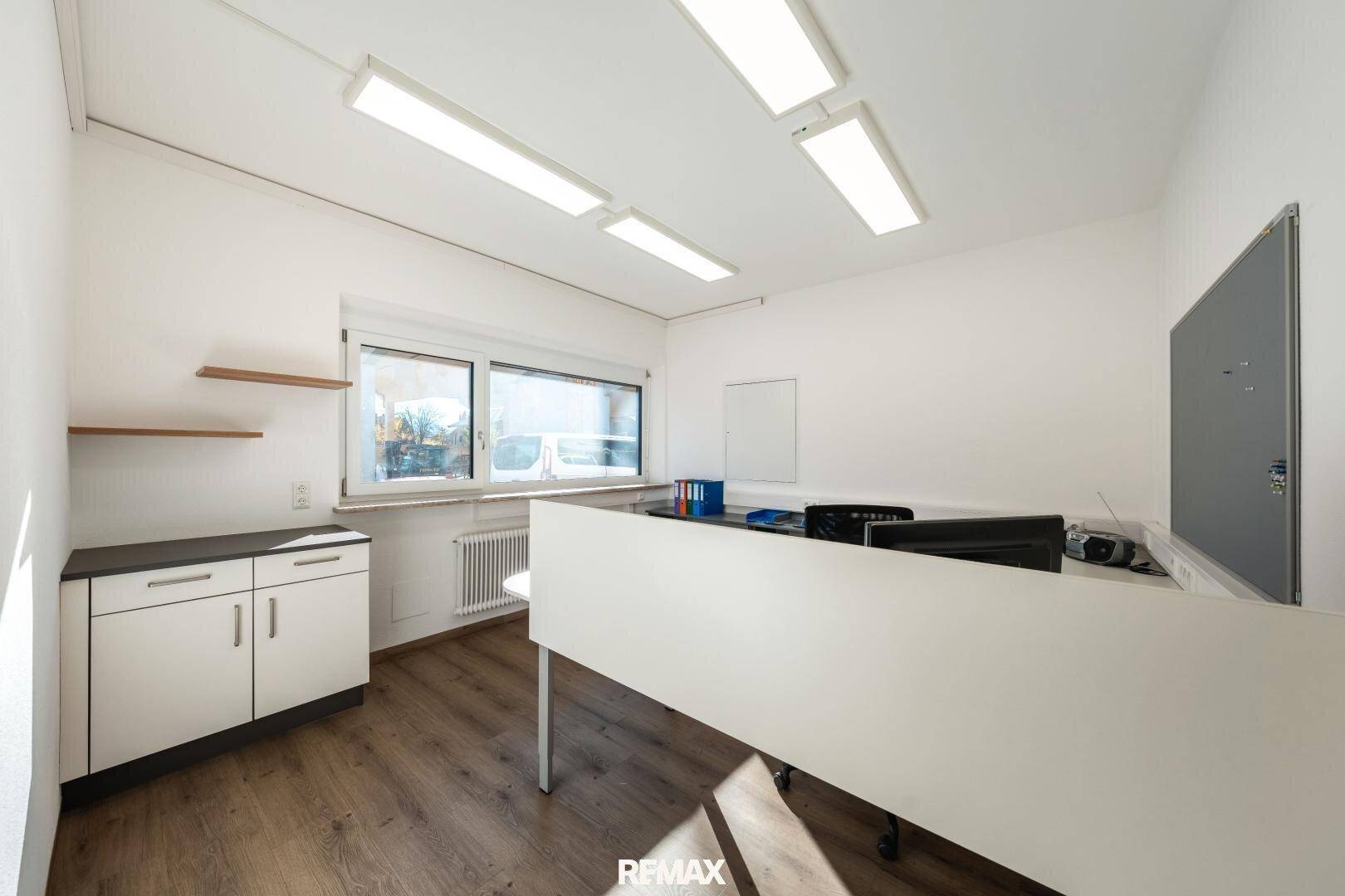 Funktionales Büro mit Schreibtisch, Stauraum, hellen Wänden und Blick nach draußen.