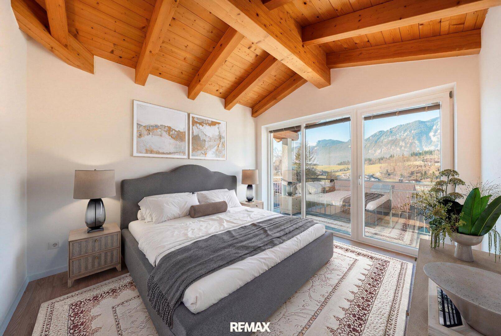 Gemütliches Schlafzimmer mit Holzbalkendecke, Bergblick und Zugang zum Balkon.