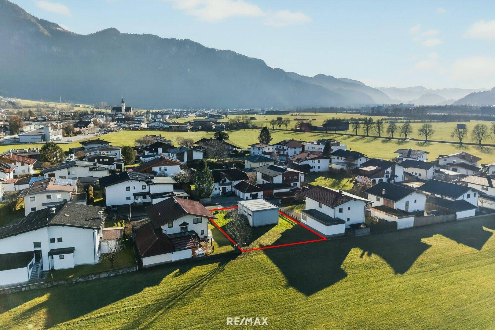 Panoramablick auf ein sonniges Baugrundstück in ländlicher Umgebung mit beeindruckender Bergkulisse.