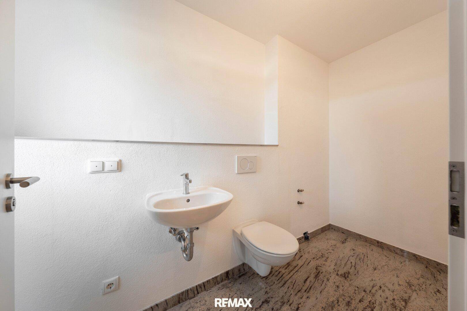 Kleines Gäste-WC mit Waschbecken, Toilette und Fliesenboden.